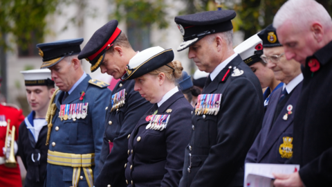 Armed forces personnel bow their heads