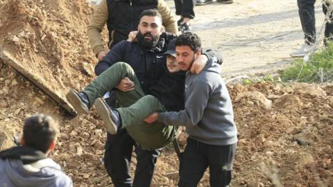 Two men carrying an injured person 