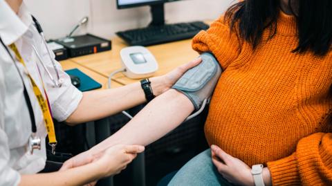 A woman has her blood pressure taken by a doctor