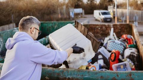 Man in purple jumper and gloves uses a tip