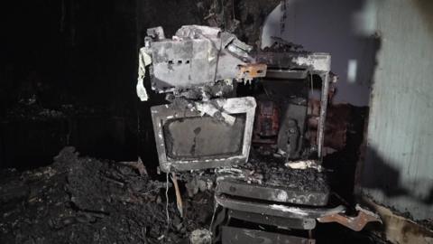 A fire damaged monitor surrounded by ash