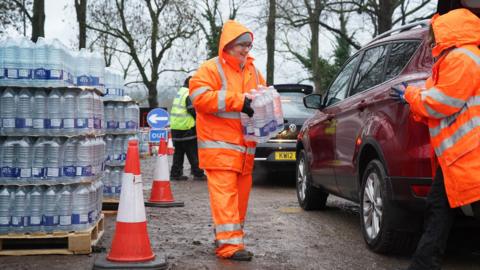 A woman passes on water by a car