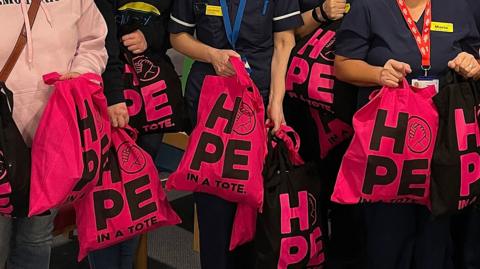 A close-up of a number of the Chemotivation charity's black and hot pink Hope in a Tote bags