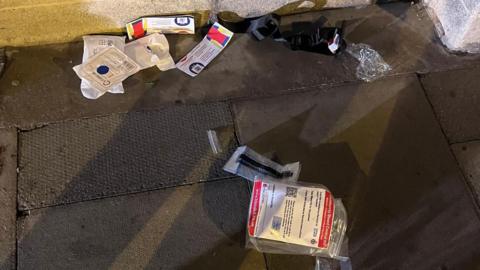 Contents of a bleed kit are on the floor and ripped open.