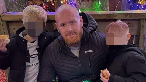 A police handout of Lenny Scott with two of his children. He is crouching down with his arms around them. The boys' faces have been blurred.