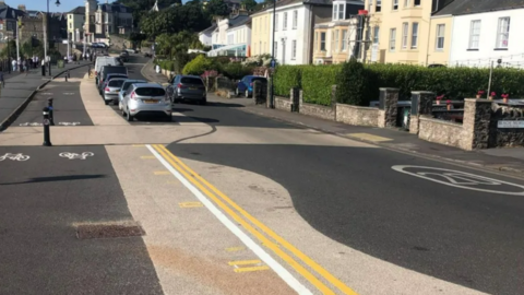 Clevedon seafront with a cycle lane and cars parked parallel to the seafront, and double yellow lines painted in the road