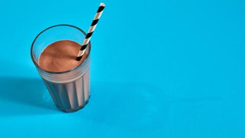 Glass of chocolate milk on blue background