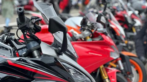 A row of motorbikes. They are predominantly red and black in colour. 