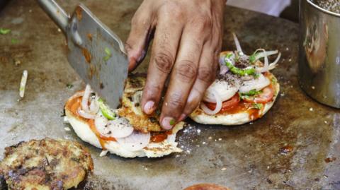 Cook preparing vegetarian burgers in Varanasi, Uttar Pradesh, India, Asia