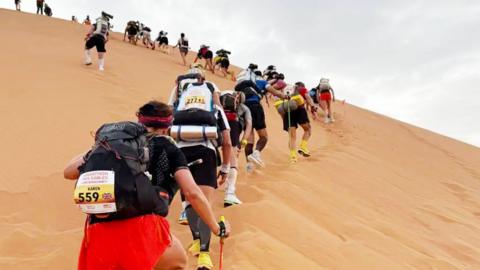 Participants climbing sand dunes in the Marathon des Sables