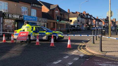 Police cordon in Evington Road, with two officers and a police car at the cordon 