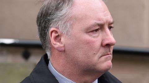 Ian Paterson - a man with grey hair with a solemn expression on his face.