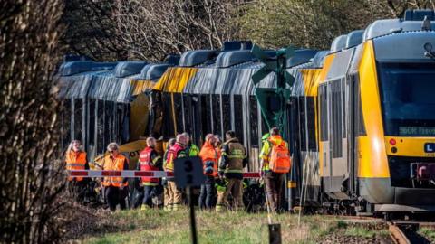 Two trains collided against each other as emergency services stand outside the crash.