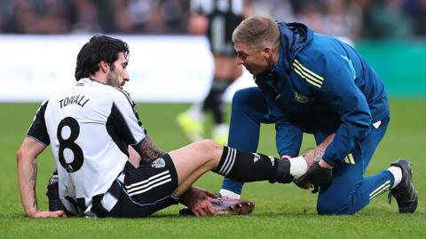 Newcastle midfielder Sandro Tonali gets treatment for an injury during the Premier League game against Aston Villa