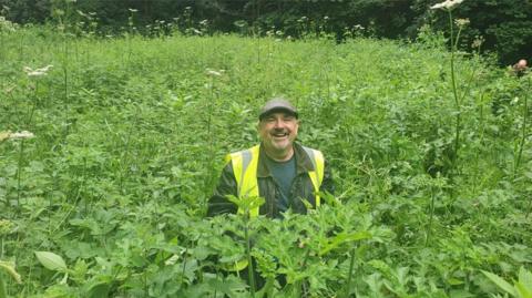 Andy McBride-Coogan among tall Himalayan Balsam plants 