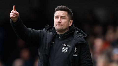 Crewe manager Lee Bell points towards his players during a game