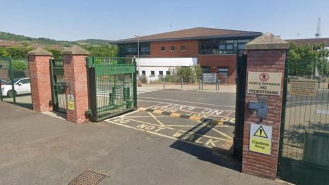 The gates of a school, with the school building in the background. 