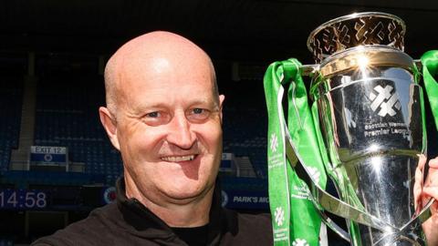 Hibernian Head Coach Grant Scott lifts the Scottish Women's Premier League trophy during a Scottish Women's Premier League match between Rangers and Hibernian at Ibrox Stadium,