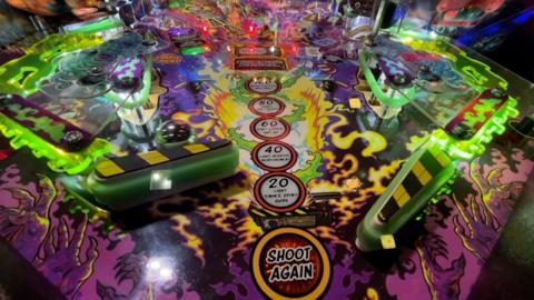Close up of pinball machine playing surface showing flippers and ball in play