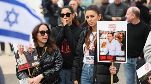 People in Tel Aviv holding placards with images of Israeli hostages (08/02/25)