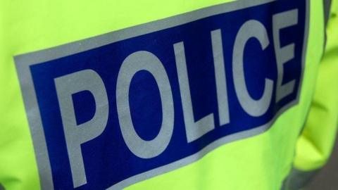A close up image of a fluorescent yellow jacket with a large blue and white police logo on it.