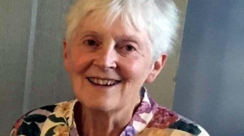 Sheelagh smiling into the camera. She is wearing a floral shirt.