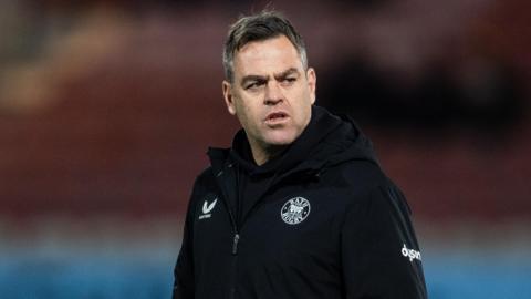 Johann van Graan walking on the pitch with his arms in his pockets during a pre-match warm-up