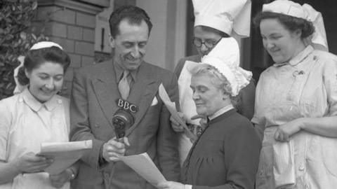 Nurses stand around a man holding a 鶹ҳ microphone