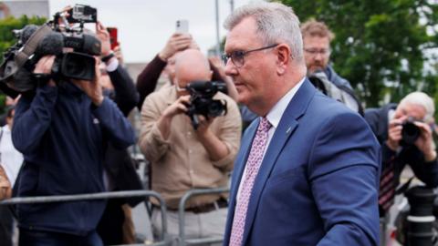 Sir Jeffrey Donaldson walks past a bank of photographers outside court wearing a blue suit