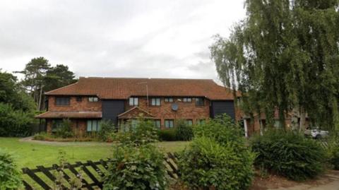 Cambridge Park Academy in Grimsby with a lawn, fencing and trees surrounding the two-storey brick building