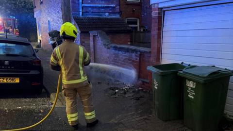 Leicestershire Fire and Rescue Service firefighter dealing with a wheelie bin fire in Loughborough, in Leicestershire, in the early hours of Monday 4 May 2026.