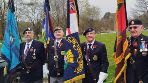 Members of the armed forces in uniform and holding flags