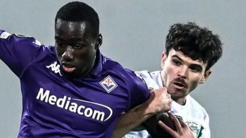 Michael Kayode of Fiorentina competes for the ball with Ben Clark of The New Saints