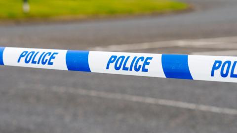 Police tape across a road.