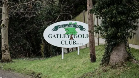 The Gatley Golf Club sign is white, with the word 'Welcome to Gatley Golf Club - est 1912' written on it in dark green.