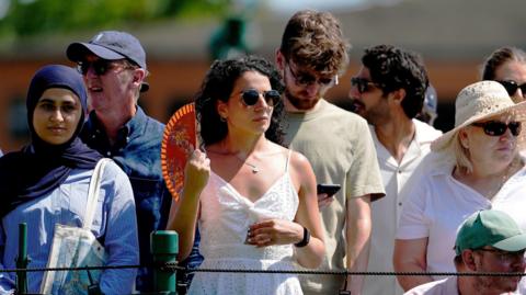  A spectator cools down with a fan on day one of the 2025 Wimbledon Championships
