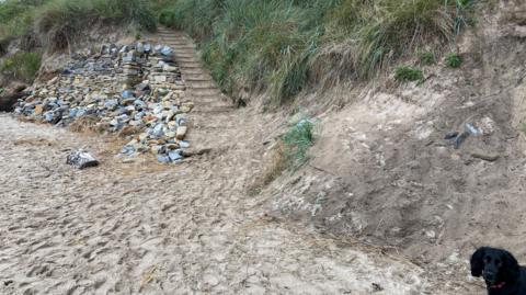 The image shows a dry stone wall with some steps leading off up onto the bank above 