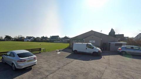 Clubhouse and cricket pitch under a blue sky