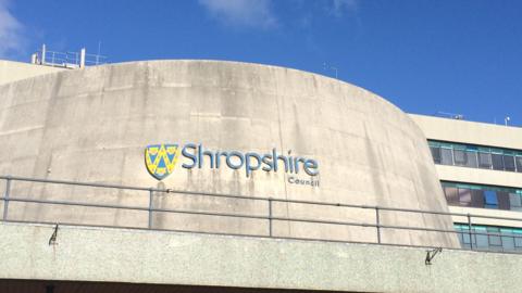 The curved concrete front of a large building with the words Shropshire Council in blue lettering