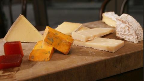 A wooden block with a variety of different cheeses laid out