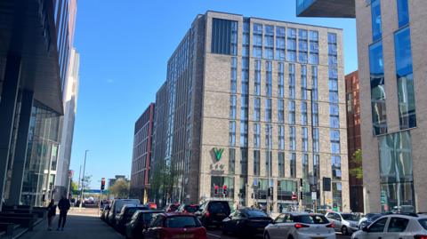 A building in the sun, there is traffic on the road