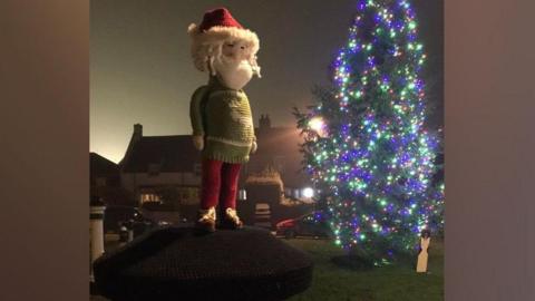 Knitted Santa topper overlooking the Christmas Tree 