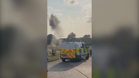 Smoke behind a police van.