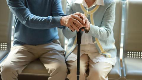 Senior couple holding hands with walking cane