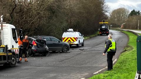 A policeman watches as vehicle recovery workers remove cars from the side of the road