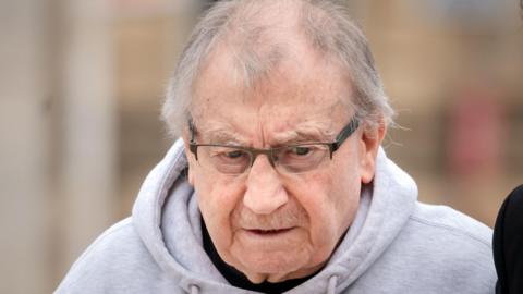 Kenneth Lingard arriving at Liverpool Crown Court in April 2025. He has grey receding hair and a moustache and is wearing glasses and a grey hoodie.