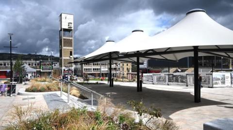 Shipley market square with covered canopies in white and a modernist concrete clock tower in the background. 