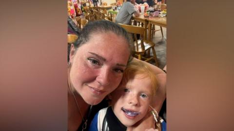 Carol Anne has freckles and tied-back brown hair while her daughter has strawberry blonde hair. They are photographed together in a restaurant.