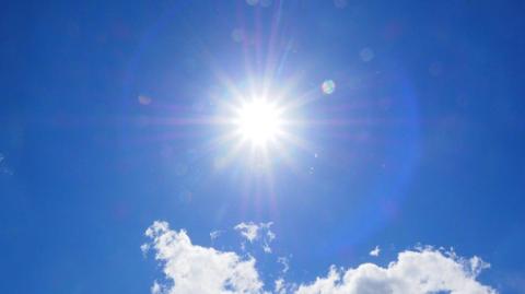 The sun shining in a clear blue sky.