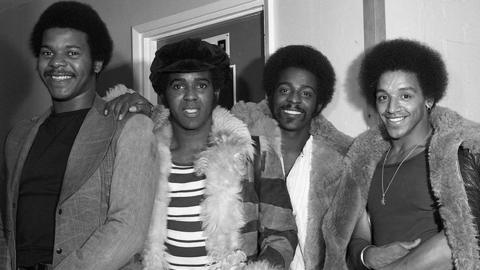 The Real Thing band with all four members of the group smiling standing side by side in an undated image estimated to have been taken in about 1976-77